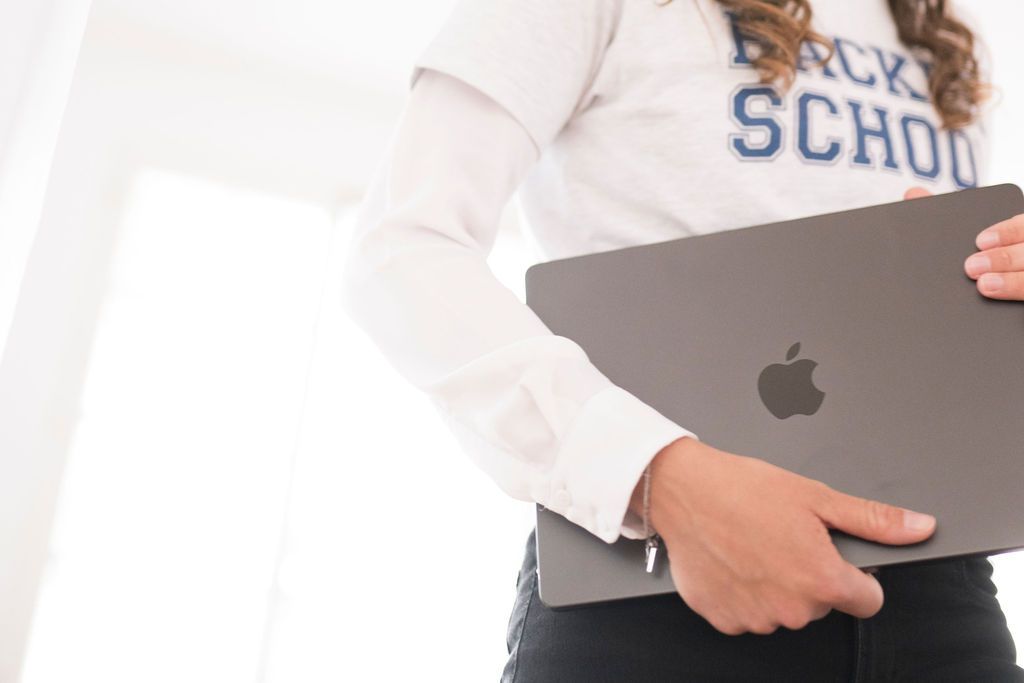 Person in a Hacker School sweatshirt carrying a closed laptop under one arm