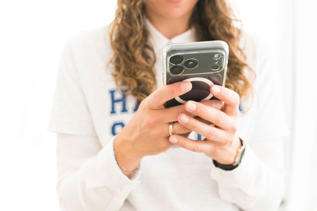 Person im Hacker-School-Sweatshirt tippt auf einem Smartphone